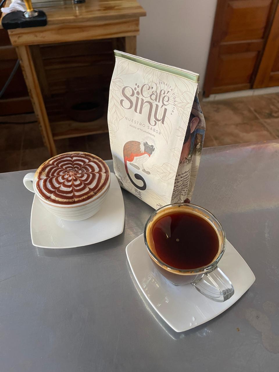 Taza de café negro y capuchino junto a la bolsa de Café Sinú